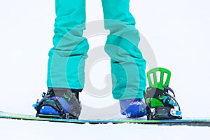 Close up of girl`s legs with snowboard and bindings.