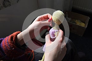 Close-up girl sews hand to her handmade crochet doll