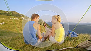 CLOSE UP: Girl shows her phone to her annoyed boyfriend and he waves at her.