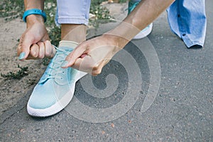Close-up of girl ties the laces on the shoes while walking around the city