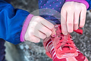 Close up of a girl tying her red shoes.