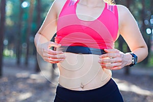 Close up of girl using heart rate monitor for workout in the forest or tracking her weight loss improvement