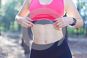 Close up of girl using heart rate monitor for workout in the forest or tracking her weight loss improvement