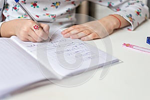 Close up of a girl writing math exercise at home. Selected focus