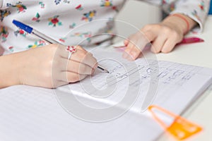 Close up of a girl writing math exercise at home. Selected focus
