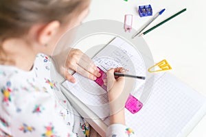 Close up of a girl writing math exercise at home. Selected focus