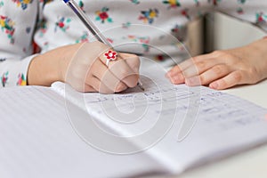 Close up of a girl writing math exercise at home. Selected focus