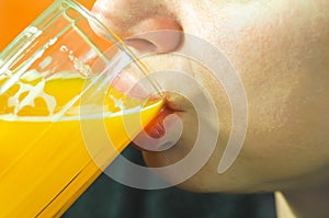Close up of girls face and lips drinking orange juice from the glass as refreshment, real people, selective focus
