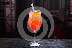 Close up of a glass of aperol spritz cocktail, standing on the bar counter,  on a red light background