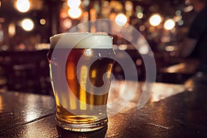 Close up of a small glass of beer with blurred background on a table with reflection