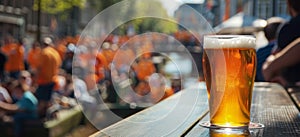 Close-up glass of beer on wooden table with blurred Amsterdam canal in the Netherlands during Kingsday holiday