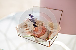 Close up glass box for wedding rings decorated with fresh rose flowers and banch of lavender. Event decoration with fresh flowers