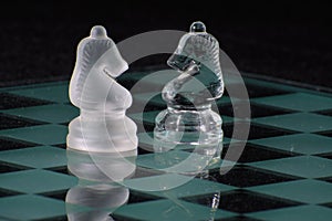 Close-up of glass chess knights on a glass chess board