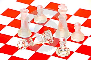 Close up of glass chess pieces on red and white chess pattern background 