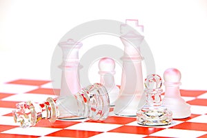 Close up of glass chess pieces on red and white chess pattern background