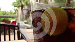 Close up of a glass of cola-colored fizzy drink with indistinct chair and bac