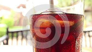 Close up of a glass of cola-colored fizzy drink with indistinct chair and bac