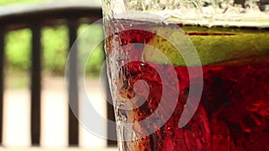 Close up of a glass of cola-colored fizzy drink with indistinct chair, backgr