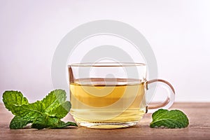 Close up a glass cup of mint tea with green fresh peppermint lea