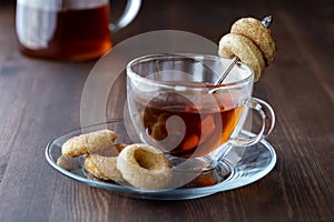 Close up of a glass cup of tea served with mini sugar and cinnamon donuts, ready for eating.