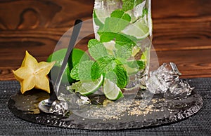 Close-up of a glass filled with alcohol beverage from juicy lime, rum, fresh mint and ice on a dark background. Copy space.