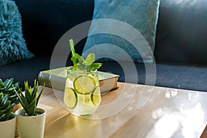 Close up a glass of gin and tonic cocktail drink on wooden table in the living room under afternoon sunlight through the window.