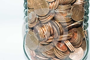 Close up of a glass jar full of coins on a white background