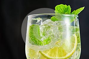 Close-up glass of mojito cocktail with ice on a dark background. Macro photography