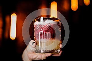 Close up glass of New York sour cocktail in a woman`s hand .