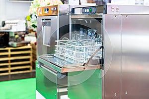 Close up glass plate and tumbler on basket in automatic dishwasher machine for industrial