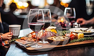 Close-up of a glass of red wine on a bar table with blurred people and charcuterie board in the background at a cozy wine tasting
