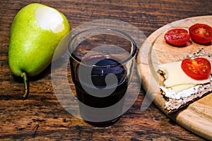 Close-up of glass of red wine with pear and bread on rustic wooden table