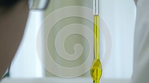 Close-up of glass tube with blue fluid in scientist hand during medical test. scientists hand holding a test-tube with