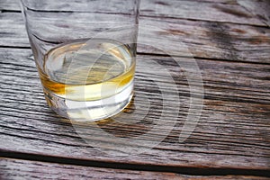 Close-up of a glass tumbler of whiskey on a wooden table