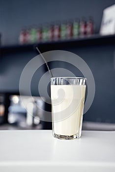 Close up of glass with white cocktail and straw. Protein shake on the counter in sports bar