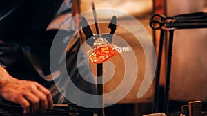 Close-up of glassblower shaping a molten glass