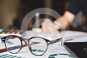 Close-up glasses is Asian young businessman of student holding a pen writing letter on paper at home