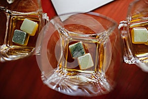 Close up of glasses of whiskey with special ice on a wooden table