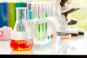 Close up Glassware with red liquid inside with test tubes and microscope in laboratory