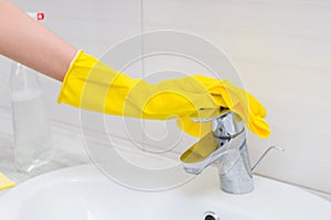 Close up of gloved hand cleaning sink