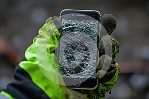 Close-up of gloved hand holding broken smartphone photo