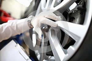 Close-up gloved hand touches the cap car wheel