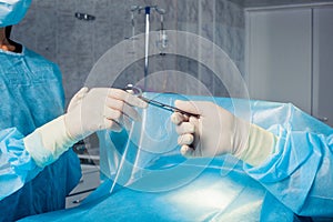 Close-up of gloved hands holding surgical scissors