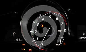 Close up glowing tachometer needle at zero engine speed on the car dashboard