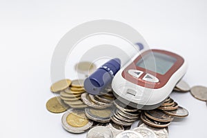 Close up of Glucode meter with lancet for check blood sugar level on pile of coins on white background. Money, Medicine, diabetes