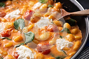 Close up of gnocchi in creamy tomato sauce with baby spinach and mozzarella