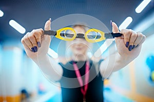 Close-up goggles for swimming in hands of trainer woman coach. Swim school for people