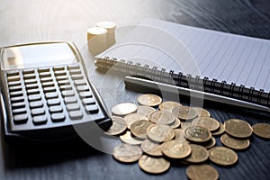 Close up gold coins, calculator, pen, notebook on black table. Business, finance, marketing, e-commerce concept and design