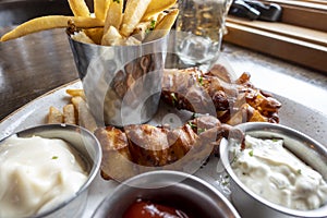 Close up of golden, battered fish fillets with thick french fries on a plate with ketchup, tartar sauce, and ranch dressings