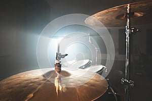 Close-up Golden cymbals Modern drum set prepared for playing in a dark rehearsal room on stage with a bright spotlight